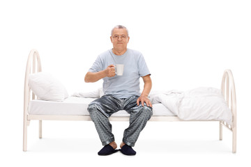 Fototapeta premium Senior sitting on bed and drinking coffee
