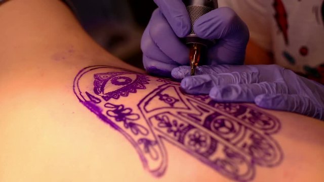 Master makes a tattoo
