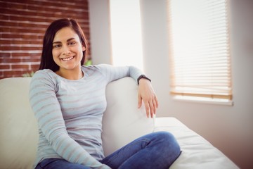 Obraz premium Portrait of smiling woman sitting on sofa