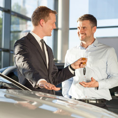 Car dealer giving client keys