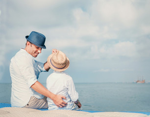 Father with son sitting on the sea pier