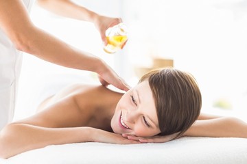 Obraz na płótnie Canvas Masseur pouring massage oil on woman