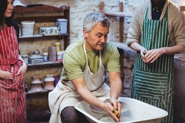 Male artist with colleagues in pottery workshop