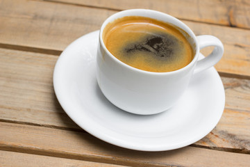 Cup of hot coffee , black coffee with foam.