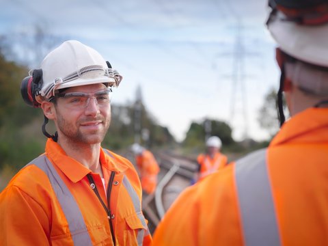 Portrait of apprentice railway maintenance worker in discussion on track