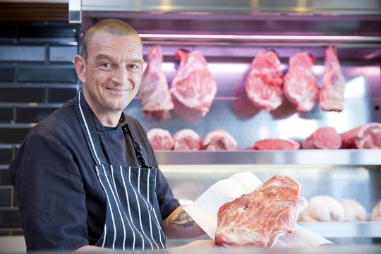 Portrait of butcher holding fresh meat in butchers shop