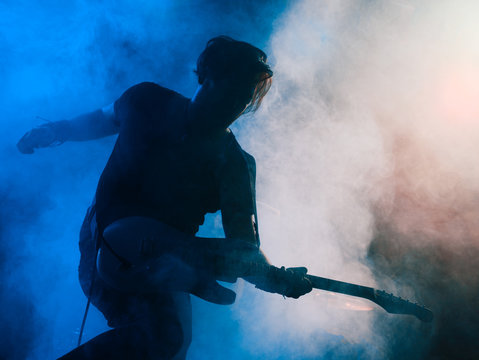 Silhouette of guitar player on stage.
