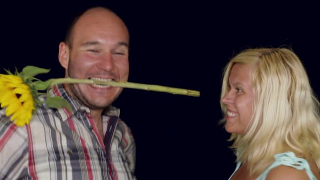 Excited couple in love dancing with sunflower, studio isolated.