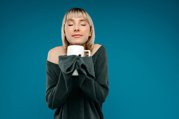 Portrait of young girl holding cup over blue background.