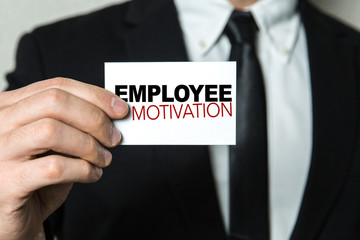 Business man holding a card with the text: Employee Motivation