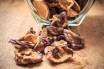 Dry mushrooms in jar on wooden table.