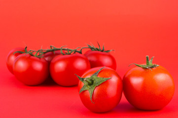 Ripe fresh tomatoes on a red background. Close-up.