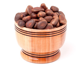 unpeeled cedar nuts in a wooden barrel on white background