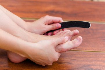 Hands making some file on feet nails, pedicure steps