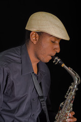 Fototapeta na wymiar Close up of man with his saxophone, feel the song with closed eyes and white hat