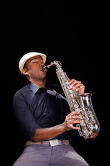 A nice view from below, black man is playing the saxophone. Professional hands with white hat