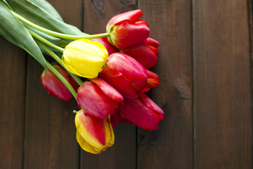 beautiful bouquet of red and yellow tulips lies on a wooden table. Fresh flowers plucked from the garden beds.