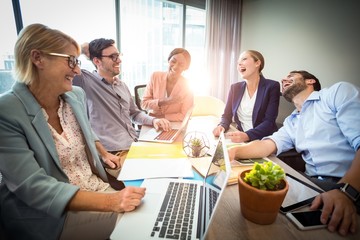 Business people laughing during a meeting - obrazy, fototapety, plakaty