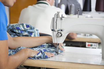 Tailor Using Sewing Machine At Workbench