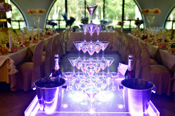 Beautiful wedding slide champagne for bride and groom indoors. Colorful glasses for alcohol with berries. Beauty of bridal interior for marriage. Bright bar for celebration