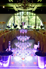 Beautiful wedding slide champagne for bride and groom indoors. Colorful glasses for alcohol with berries. Beauty of bridal interior for marriage. Bright bar for celebration
