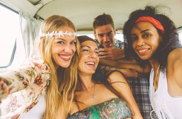 Hippie friends having fun into a vintage van, taking nice pictures