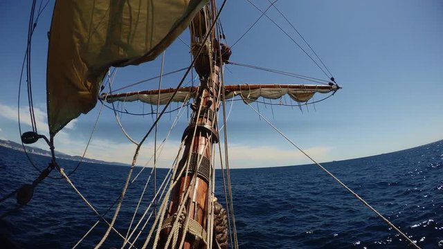 View from nose of old vintage sailing ship waving in deep blue sea with ropes and maintenance thing in air