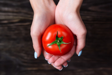 The girl in the hands holding a tomato