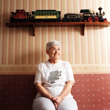 Portrait of senior woman with train set on shelf