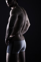 Fototapeta premium beautiful men's sporty body in backlight on the black background