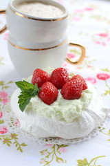 Pavlova cake with strawberries with a cup of cappuccino on a colorful napkin
