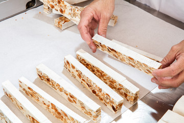 professional hands preparing freshly cut French almond nougat bars