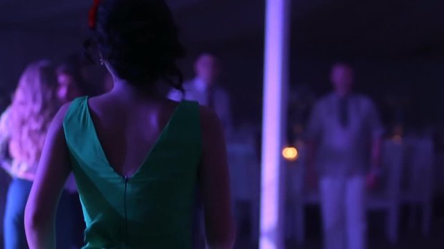 people dancing in a dark banquet hall for a wedding reception.