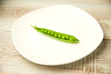 Green pea pod on the  big white plate.