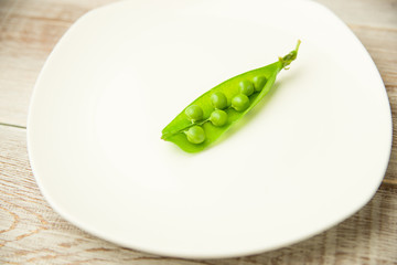 Green pea pod on the  big white plate.