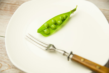 Green pea pod on the white plate.