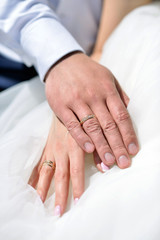 Wedding couple is holding hands. Beauty bride with groom. Beautiful model girl in white dress. Man in suit. Female and male portrait. Close-up woman's arms. Cute lady and guy indoors