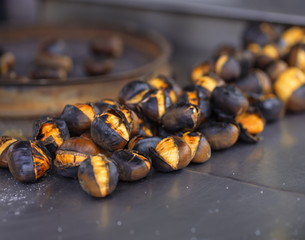 Macro roasted chestnuts with salt om metal surface.