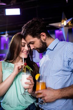 Couple embracing each other at bar counter while having cocktail