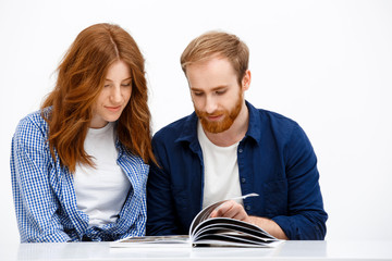 Beautiful redhead girl and boy sitting at white table. Isolated 