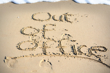 Out of office text written in sand on a beach suggesting work life balance