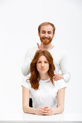 Funny redhead girl and boy sitting at white desk 