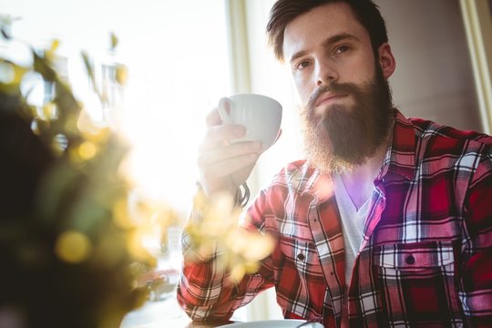 Young man holding coffee cup while sitting in cafe