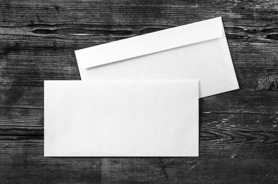 Blank white paper envelopes. template. Photo of blank envelopes on dark wooden background. Two envelopes. Back and front view. Template for ID. Top view.