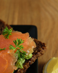 Salmon Slices with Avocado Paste and Parsley on Rye Bread. Wooden Surface.