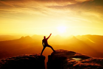 Slim tourist gesture triumph on sharp peak of rocks