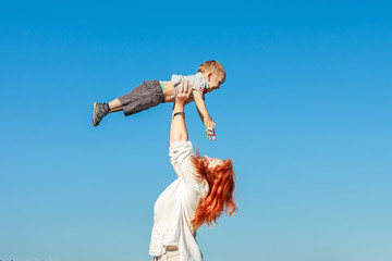Beautiful red-haired mother playing with her baby.