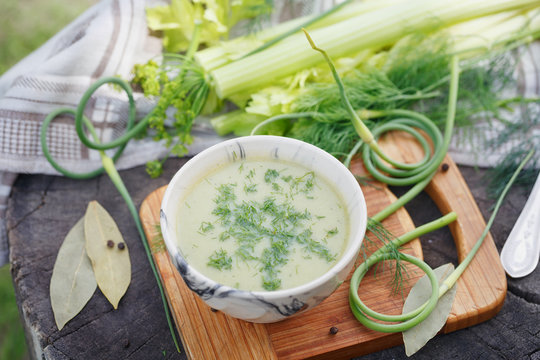 Bowl of green cream soup on wooden table