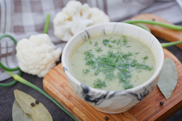 Bowl of green cream soup on wooden table