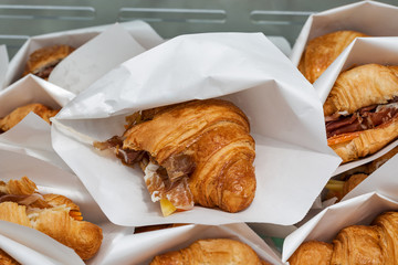 Croissants with jamon and cheese served in paper bags closeup